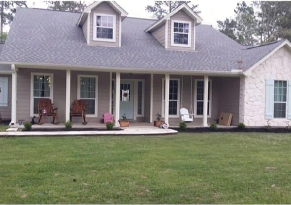 a large house with two front porches and chairs on the lawn