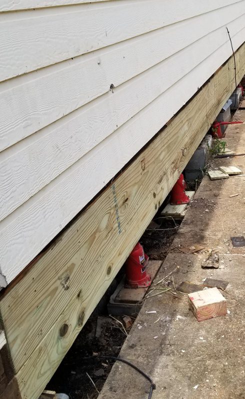 the side of a white house with a red fire hydrant next to it