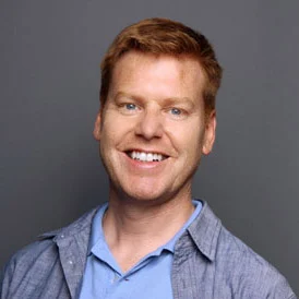 a man with red hair and blue shirt smiling