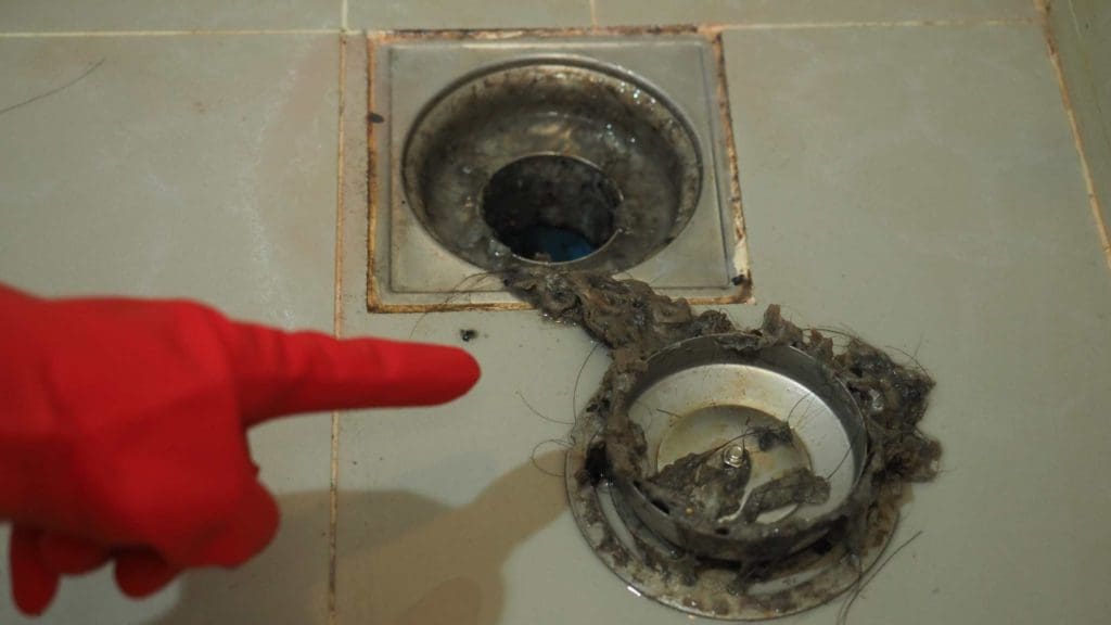 a person in red gloves is pointing at a drain