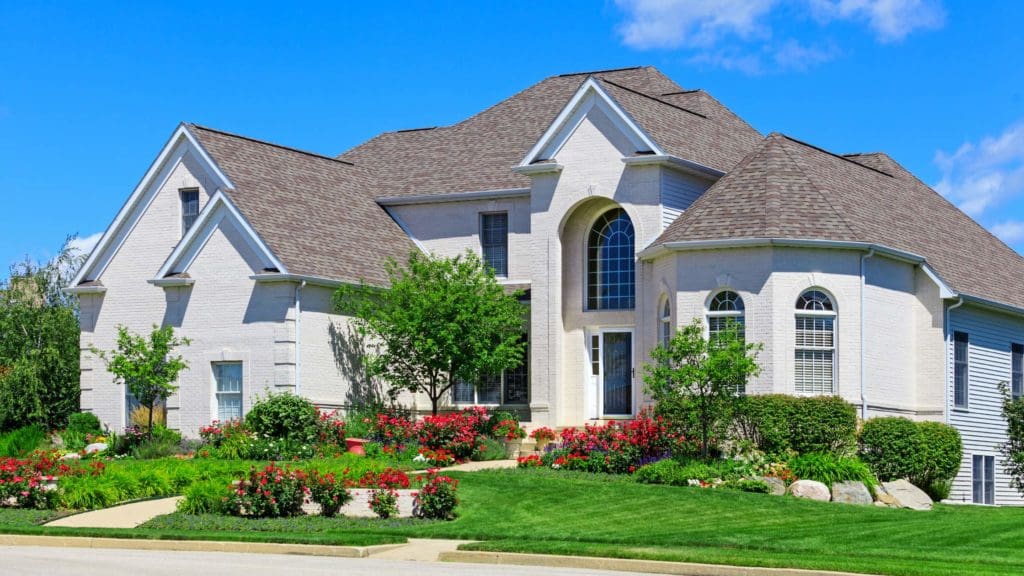 a large white house with lots of flowers in the front yard