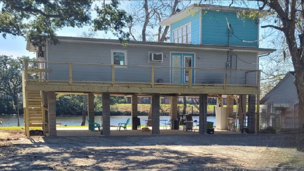 a house that is on stilts next to a body of water