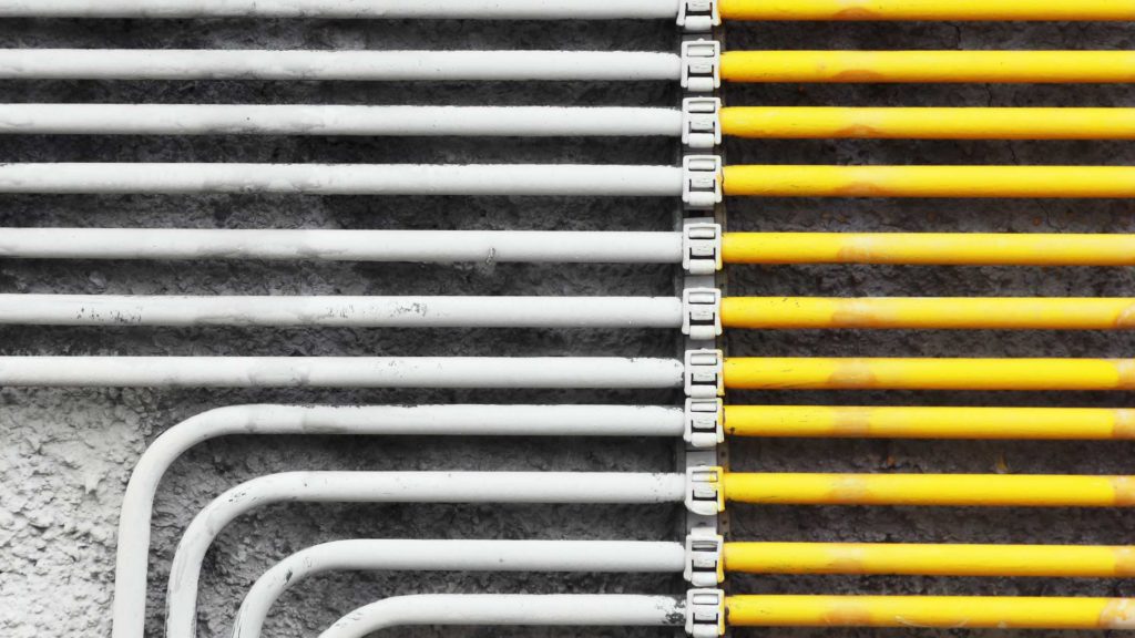 yellow and white pipes are lined up against the wall